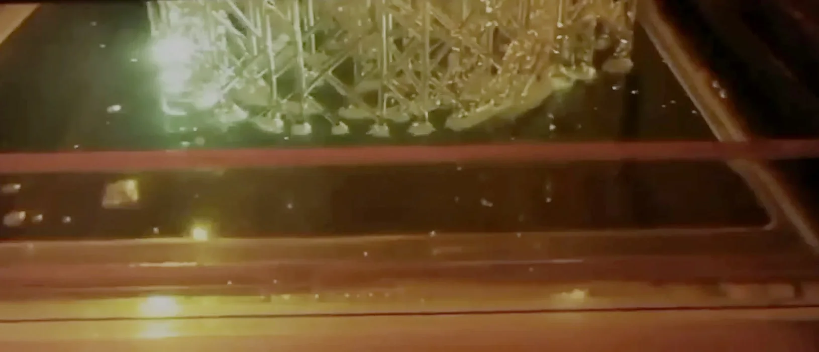 SLA 3D štampa u radu — laser očvršćava sloj smole ispod dela sa potpornom strukturom